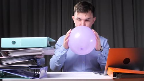 Office Worker Inflating Balloon at Desk to Relieve Stress
