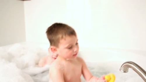 Irmãos caucasianos alegres desfrutando de um divertido banho de espuma dentro de casa