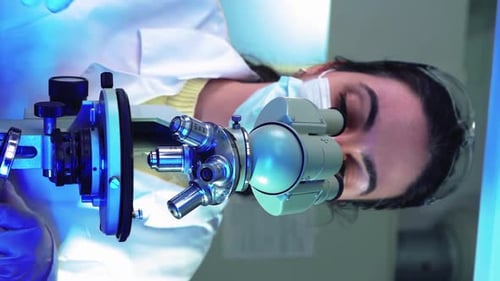 Female Microbiologist Looking Into Microscope in Medical Science Laboratory