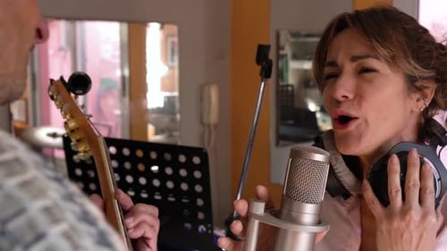 Woman Sings in Recording Studio with Guitarist