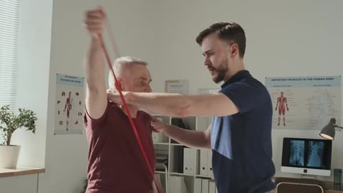 Therapist Helping Senior Man Stretch With Resistance Band