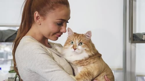 Joyful Woman Embracing Her Charming Ginger Cat with a Radiant Smile
