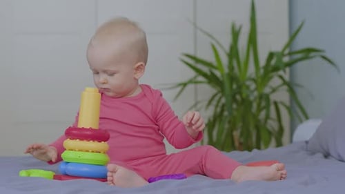 Infant playing with colorful stacker toy on bed
