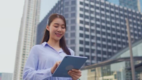 Asian young businesswoman using digital tablet while standing in the city.