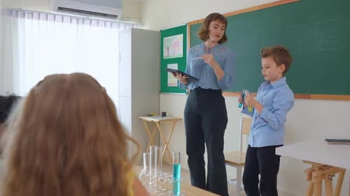 Adorable student learn with teacher in classroom at elementary school.