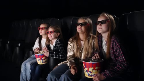 Unexpected moment. Four kids sitting in the cinema and eating popcorn