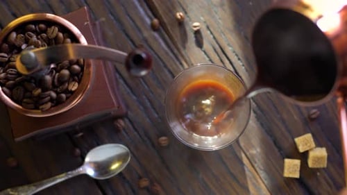 Freshly brewed coffee from cezve is poured into a coffee cup.