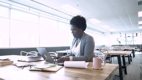 Businesswoman checking email and working at laptop in modern coworking office