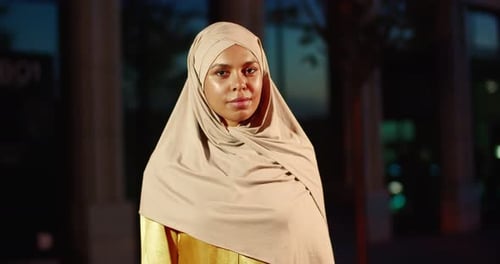 Porträtaufnahme einer jungen lächelnden schönen Araberin im traditionellen Hijab, die draußen auf der Straße steht
