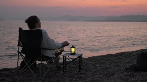 Mujer relajándose en una silla de playa viendo la puesta de sol, Grabaciones de stock Incluyendo: Puesta de sol y mar - Envato