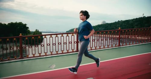 Woman Running on Bridge in Urban Setting