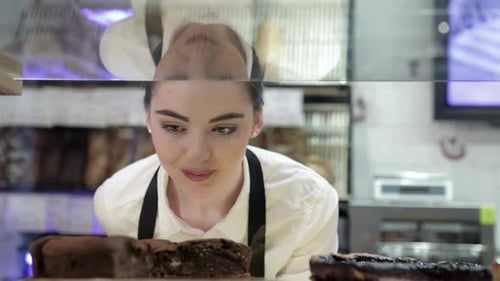 Woman Looks at Cakes in Bakery Display Case