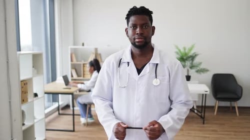 Confident Male Doctor in White Coat Standing in Modern Medical Office