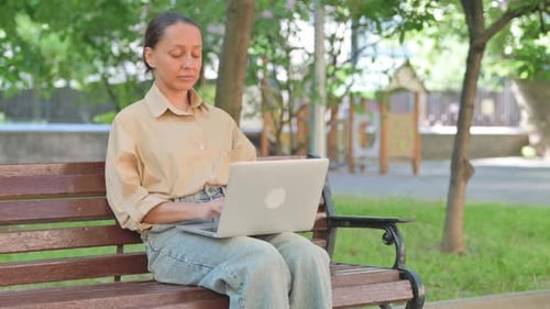 Young Woman Smiling with Laptop in Park