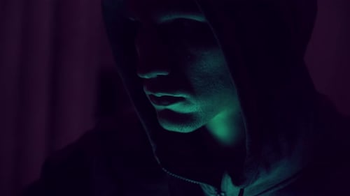 Portrait of an intimidating male hacker in a hood. nervous look. close-up.