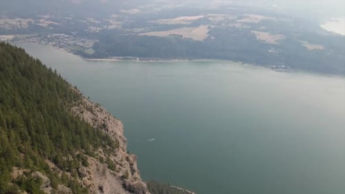 Beautiful view of pine trees on top of a mountain with a lake as background. Peaceful drone footage