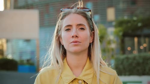 Jeune femme confiante avec des lunettes de soleil regardant directement la caméra dans un moment lumineux et animé