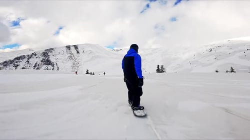 Snowboarder descends snowy mountain slope on winter day