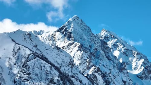 Sharp snow-covered mountain peak against a blue sky