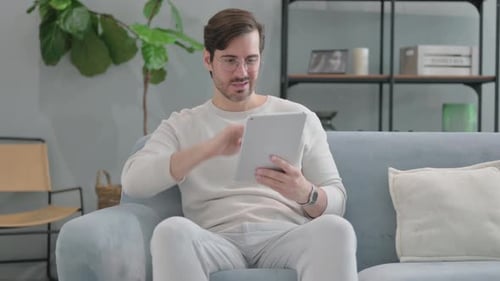 Man Frustrated with Tablet on Couch Indoors