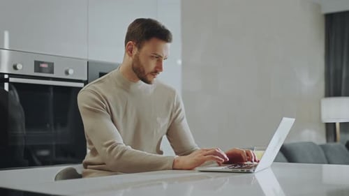Man Works on Laptop at Modern Kitchen Island