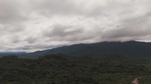 Aerial drone fly-over green forest and hills, dramatic cloud