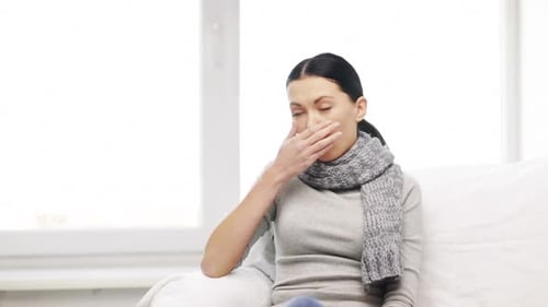 Woman Coughing on Couch at Home in Daylight