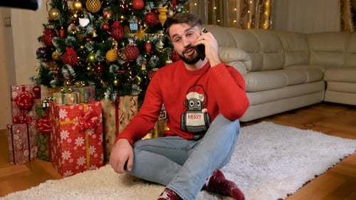 Man Chatting on Phone Near Christmas Tree