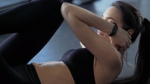 Femme brune athlétique faisant des crunches pour le fitness, la force et la musculation au gymnase