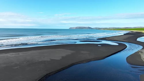 Aerial Drone View of River Flowing Into the Ocean on a Serene Black Sand Beach