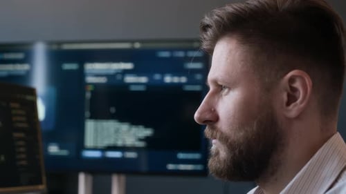 Ingénieur réseau de sexe masculin analysant les logiciels de cybersécurité sur les ordinateurs de bureau