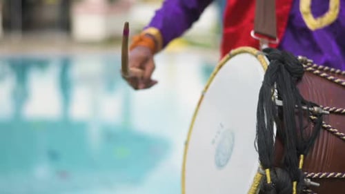 Closeup view of an Indian man playing dhol at a wedding event. Slow motion view.