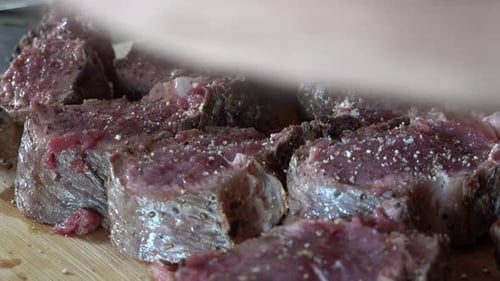 Seasoning Raw Beef Chunks on Wooden Board