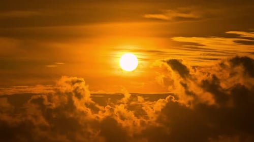 Zeitraffer eines dramatisch Sonnenaufgangs mit orangefarbenem Himmel an einem bewölkten Tag.