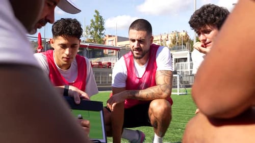Soccer Coach Explaining Strategy to Players on Field