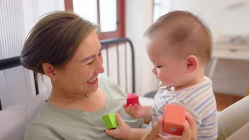 Woman Plays with Baby on Bed Indoors