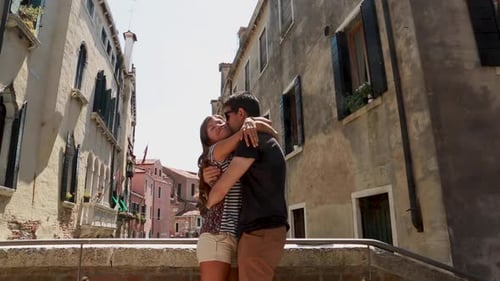 Young tourist couple hugging in a romantic way in a bridge in Venice, Italy