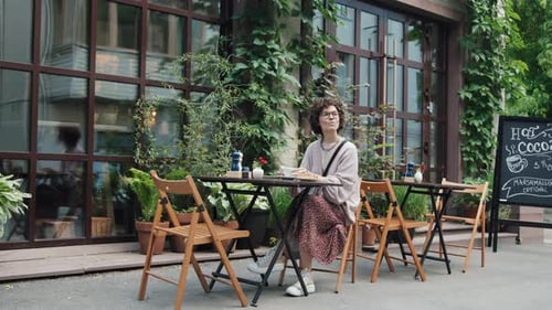 Serene Caucasian Woman Eating Croissant with Coffee in Outdoor Cafe