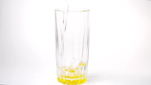 Water Filling a Clear Glass with Yellow