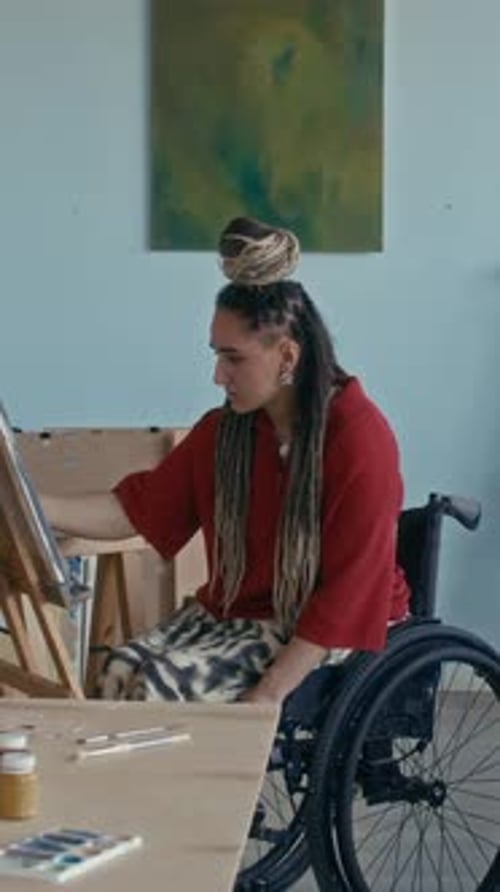 Vertical of Dedicated Female Artist with Disability Drawing on Canvas in Studio