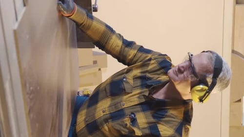 Vertical Video of Adult carpenter cuts wood in the carpentry shop.