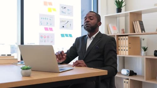 African Man in Headset Using Laptop for Video Call at Office