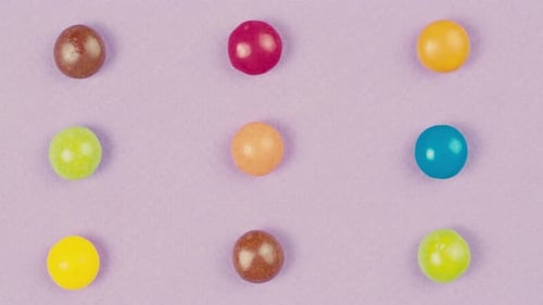 Colorful Dragee Candies with Glitter Sprinkles on Purple Background Summer Bright Texture Studio