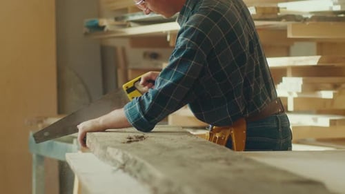 Carpenter Sawing Wood at Workbench Indoors