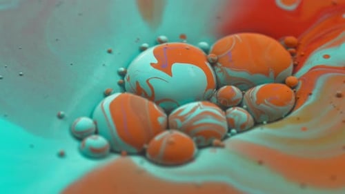 Des macrobulles bleues et oranges coulant dans de la peinture liquide