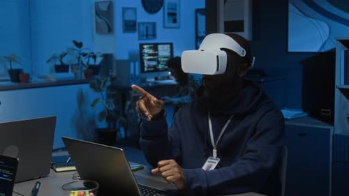 African American Developer Using VR Headset to Do Programming in Dark Office