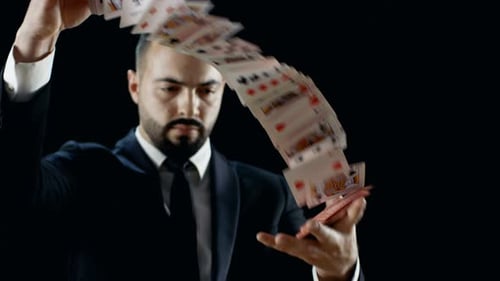 Close-up of a Professional Magician in a Black Suit Performing Card Trick. Throwing and Catching Ca