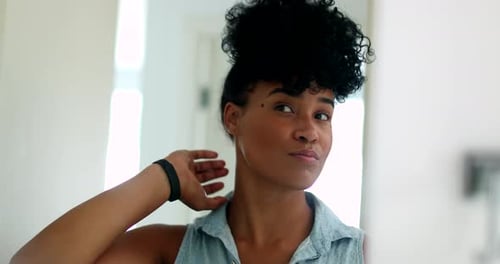 Woman Adjusting Curly Hair in Mirror at Home
