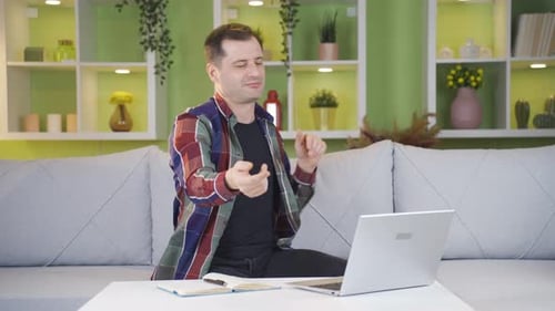 The man with the laptop in front of him starts dancing while looking at the screen.