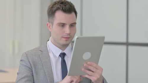 Excited Man Celebrating Success Using Tablet in Office